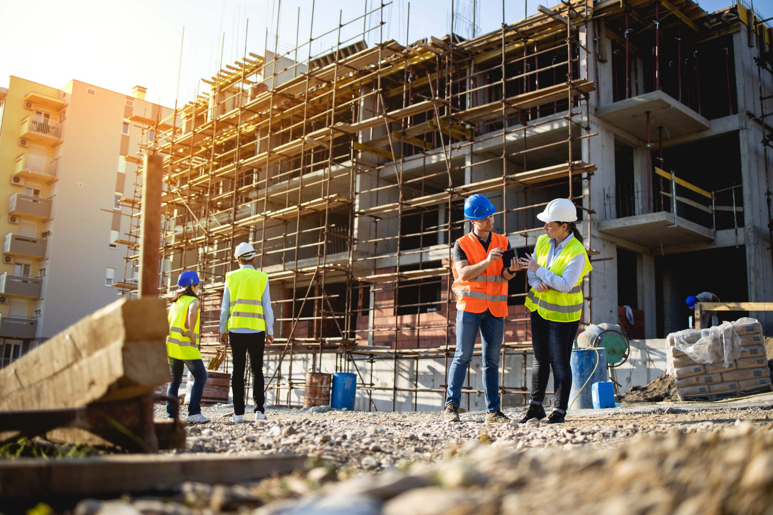 Construction site with workers in safety vests and hard hats reviewing project details, representing Paul Feely Associates' commitment to health, safety, and compliance on construction projects