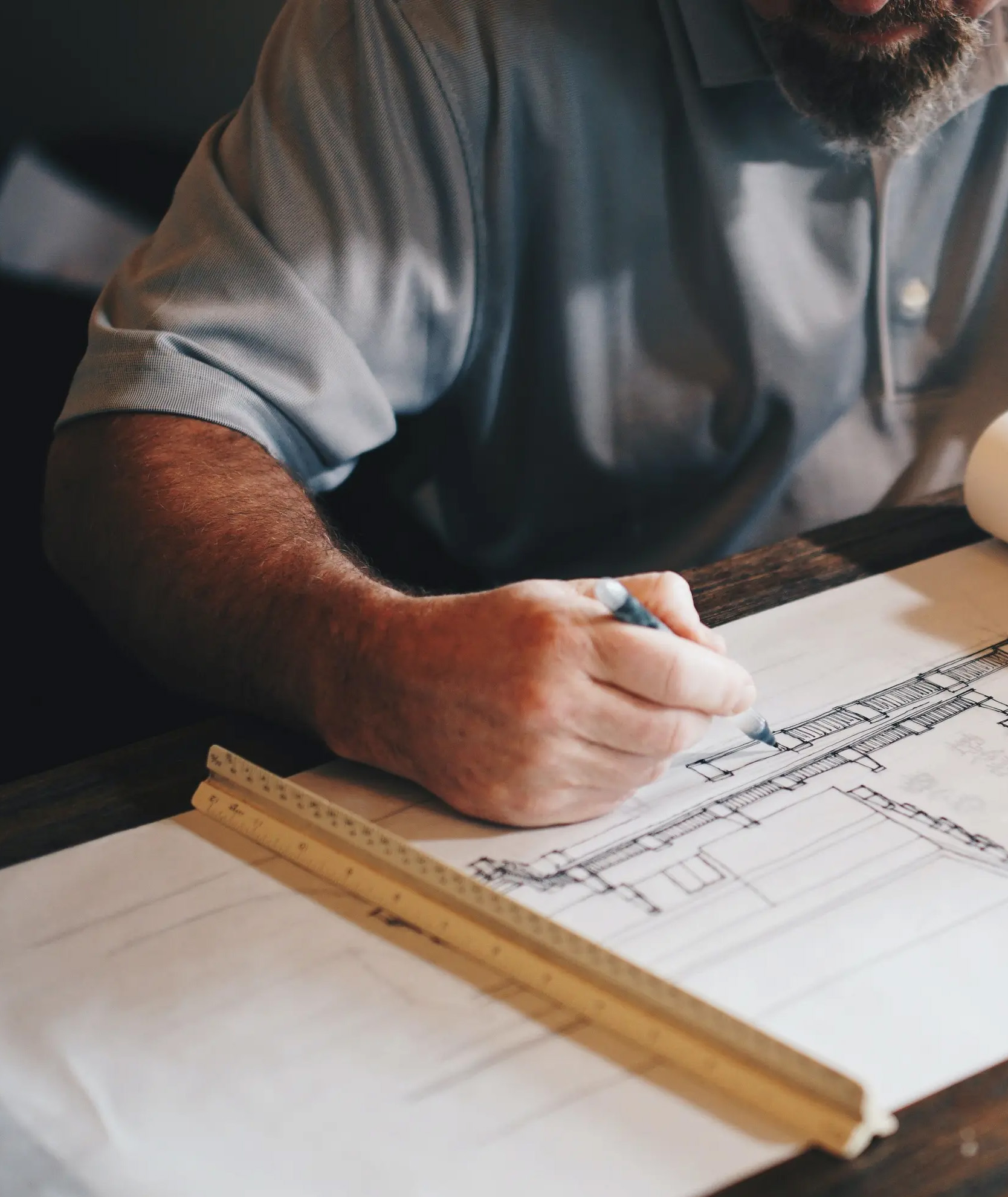 Close-up of an architect working on technical drawings, illustrating PSDP services for overseeing safety during the design stage of construction projects.